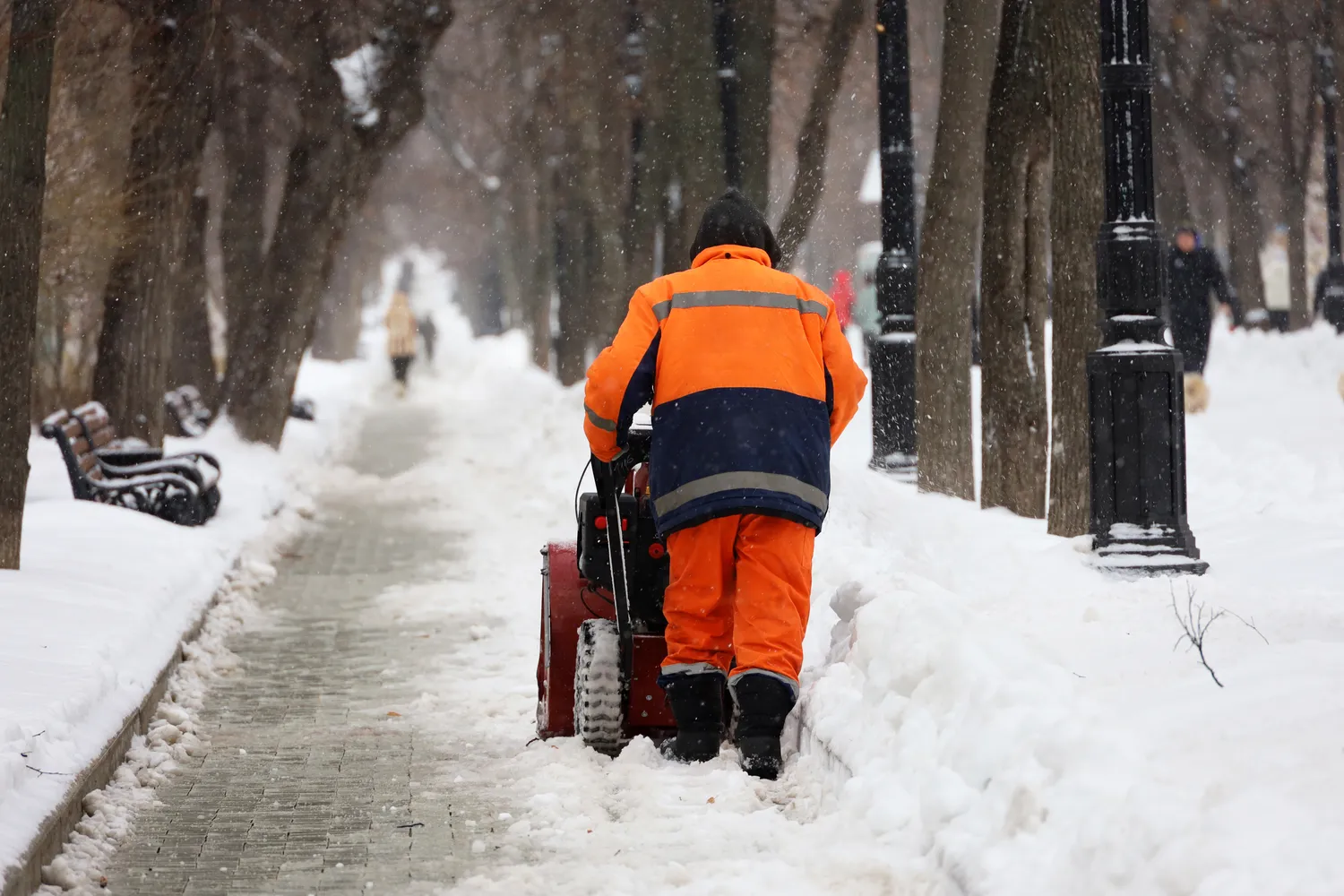 Max Pflughaupt – Hausmeisterservice – Ein Mitarbeiter des kommunalen Dienstes in Uniform räumt mit einem Schneepflug einen Gehweg vom Schnee.